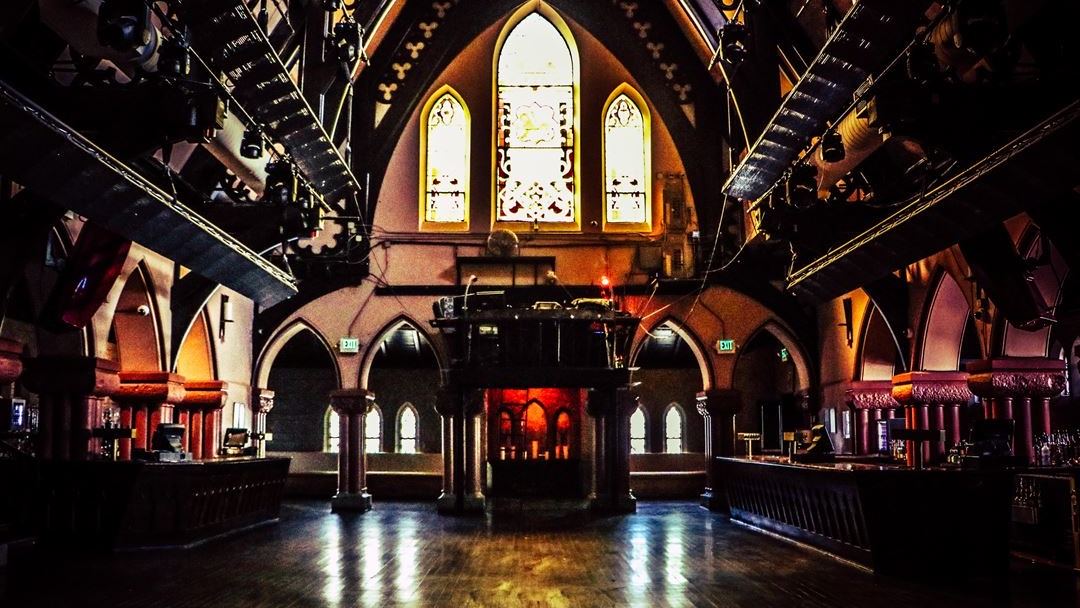 The interior of The Church, a stained glass window glowing above the main floor and bar.